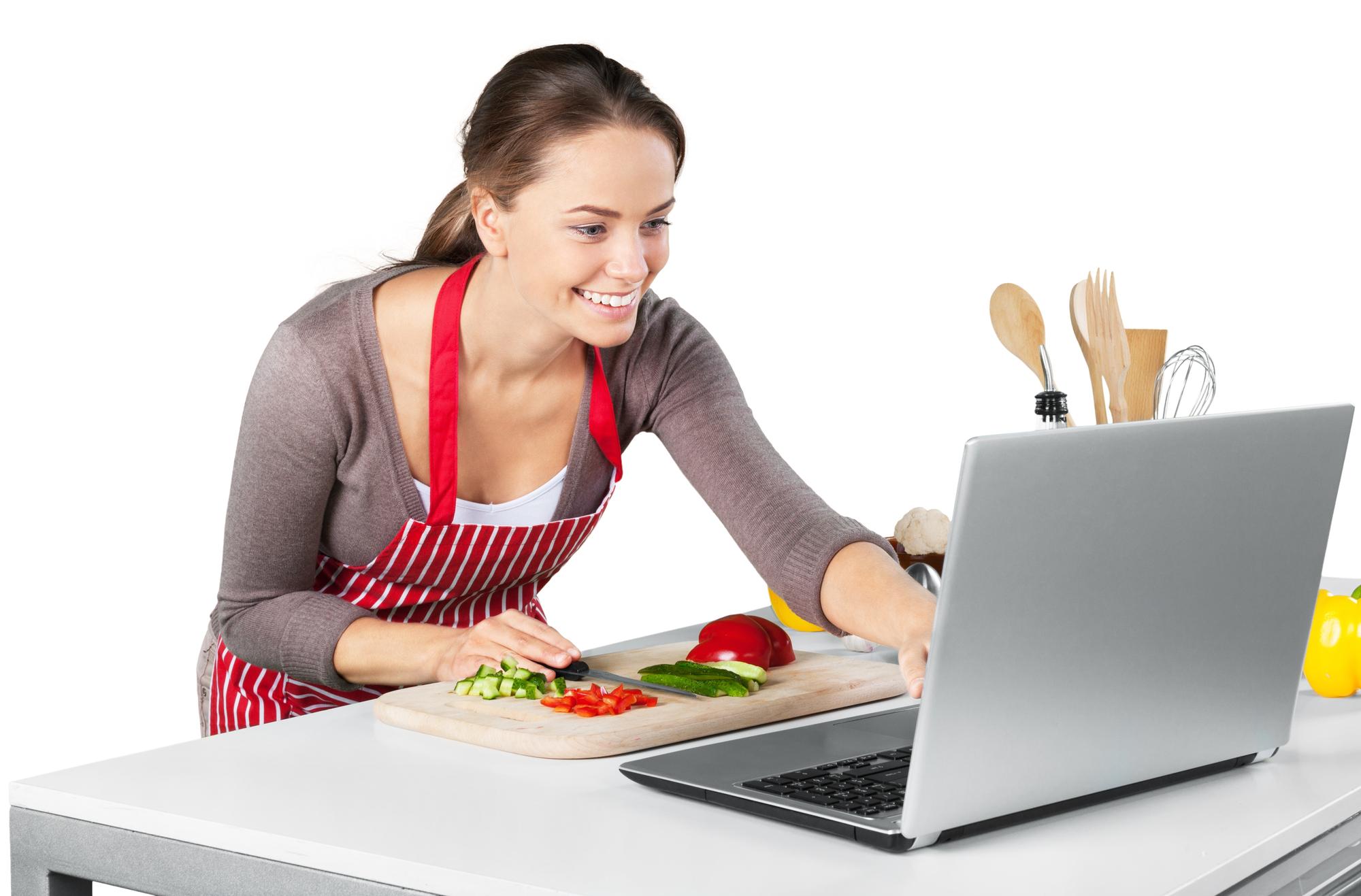 Student cooking with laptop in kitchen